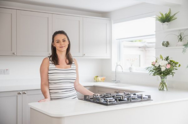 Megan customer testimonial image in her kitchen with Bluetta Carrara Quartz worktops visible around the hob