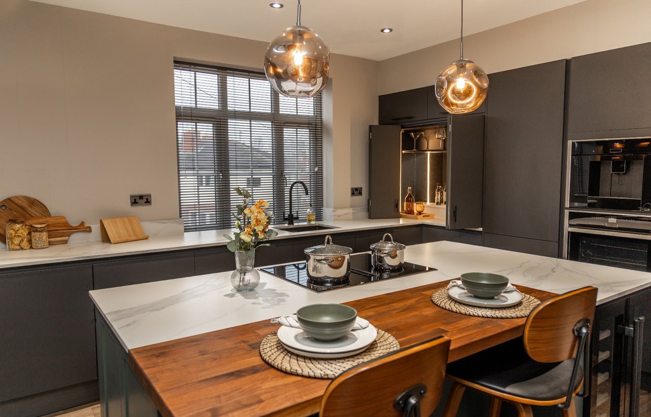 Volakas White Porcelain island worktop with subtle grey veining, shown with pendant lighting and dining place settings.