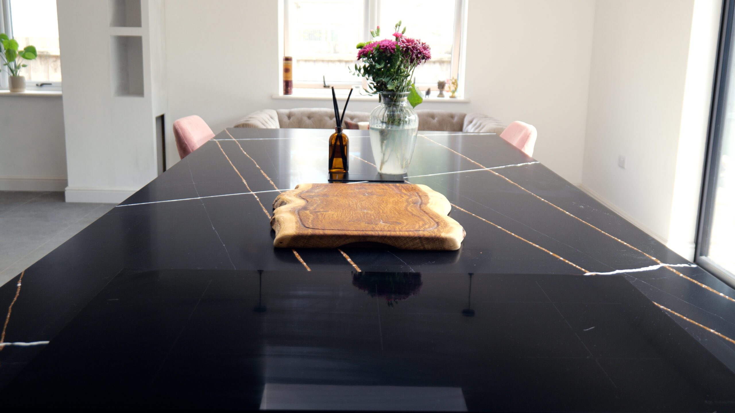 Sahara Noir Quartz island worktop with polished black surface, gold-toned line pattern and white veining shown with a wooden board