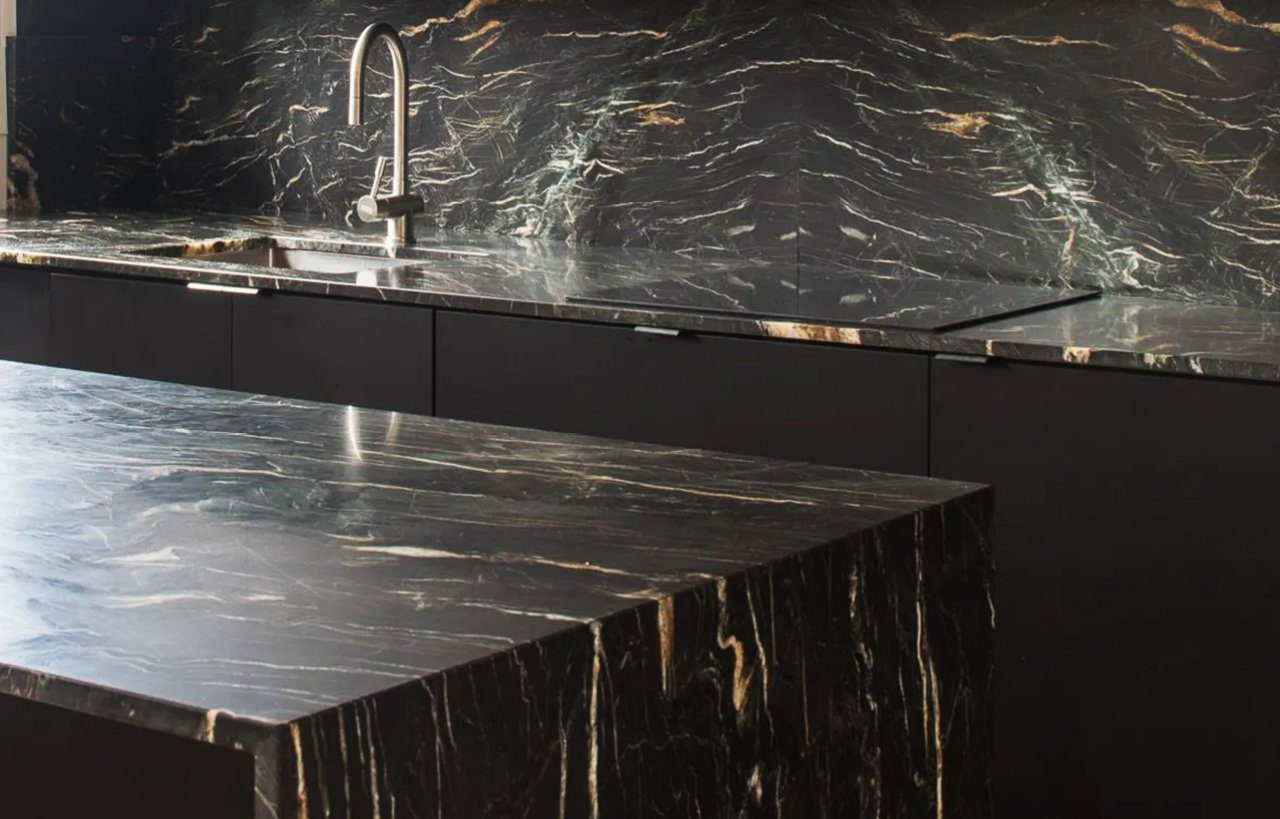 Modern kitchen view with African Fusion Granite worktops and matching full height splashback, showing dramatic gold veining across the dark Granite surface.