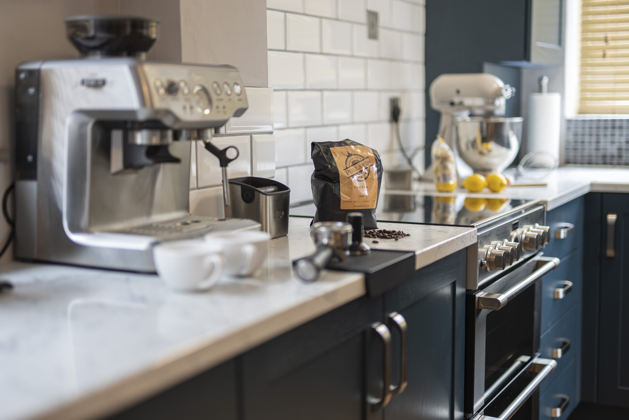 Arabescato Quartz worktop in a dark kitchen run showing grey veining beside small appliances and coffee items