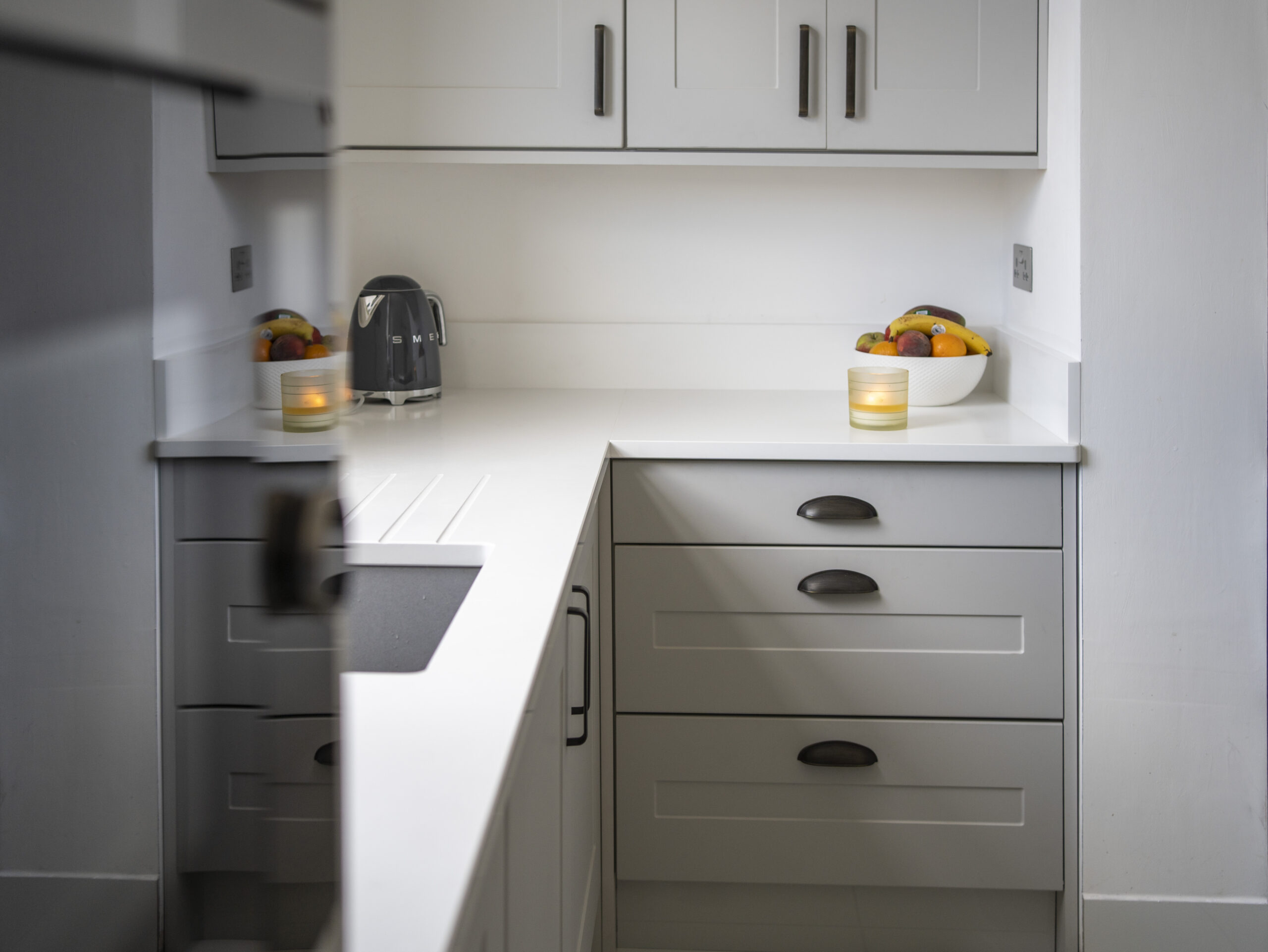 Classic White Quartz worktop run in a modern kitchen with grey cabinetry, showing a smooth white finish