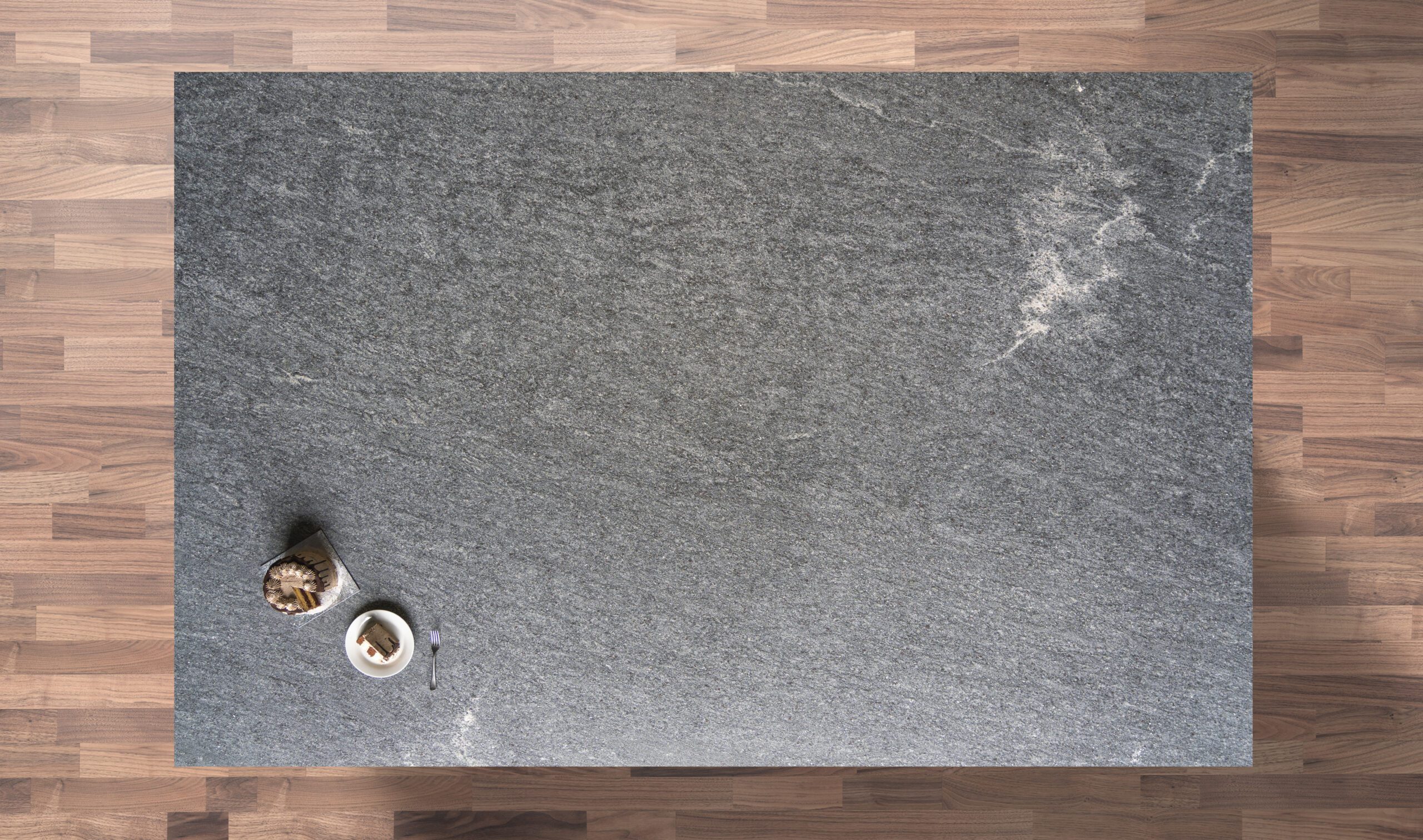 Overhead view of Diamond Galaxy leather Granite worktop showing a dark grey textured surface with subtle natural movement, photographed from above with styling near the edge.