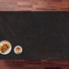 Kelya Porcelain worktop in deep charcoal with fine white veining, styled with a coffee cup and snack bowl