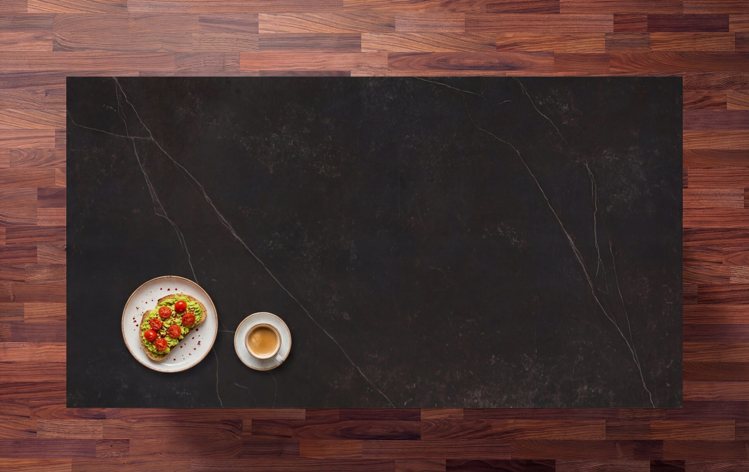Kelya Porcelain worktop in deep charcoal with fine white veining, styled with a coffee cup and snack bowl