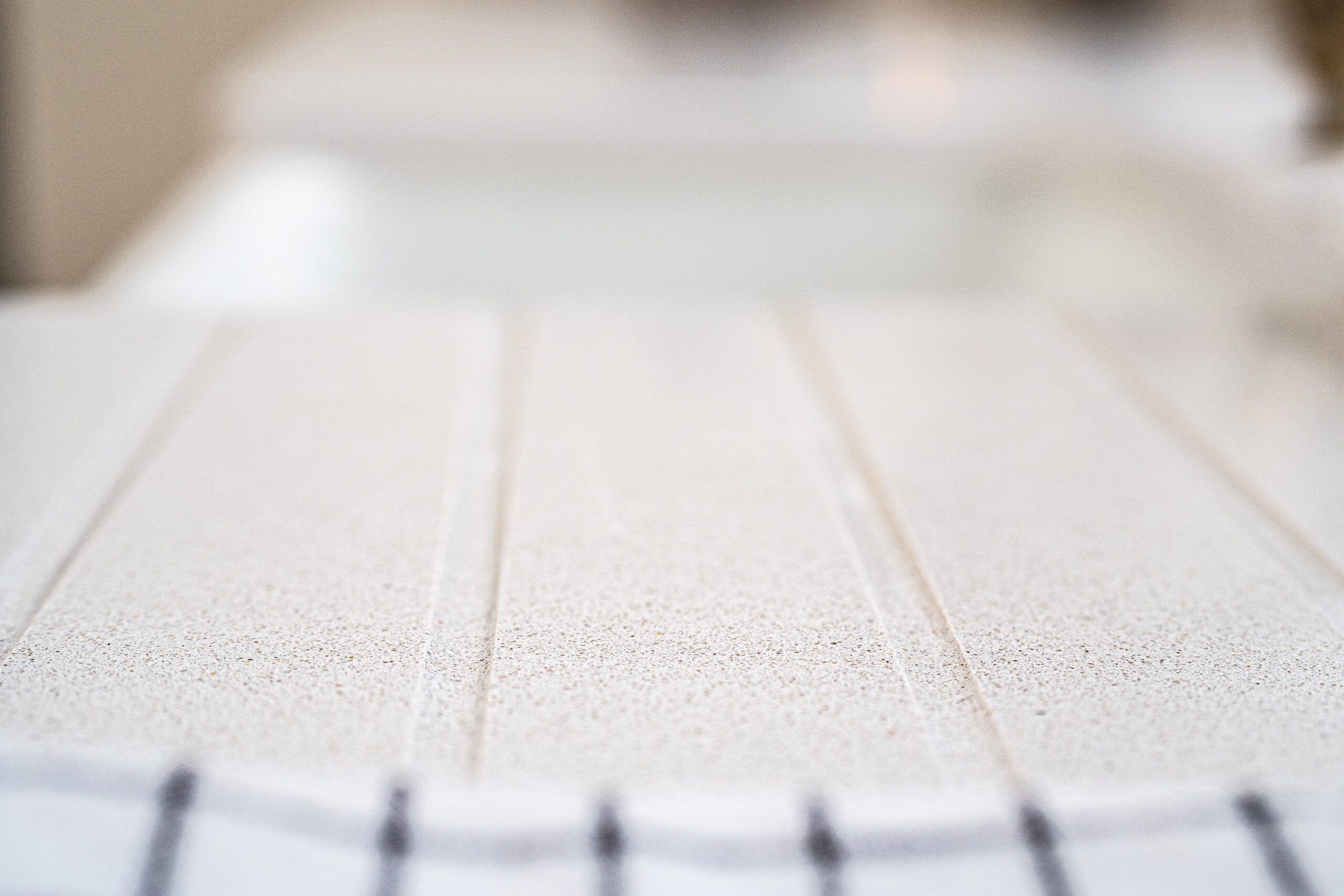 Low-angle close-up of Ice White Quartz drainer grooves showing the clean channel lines across the surface