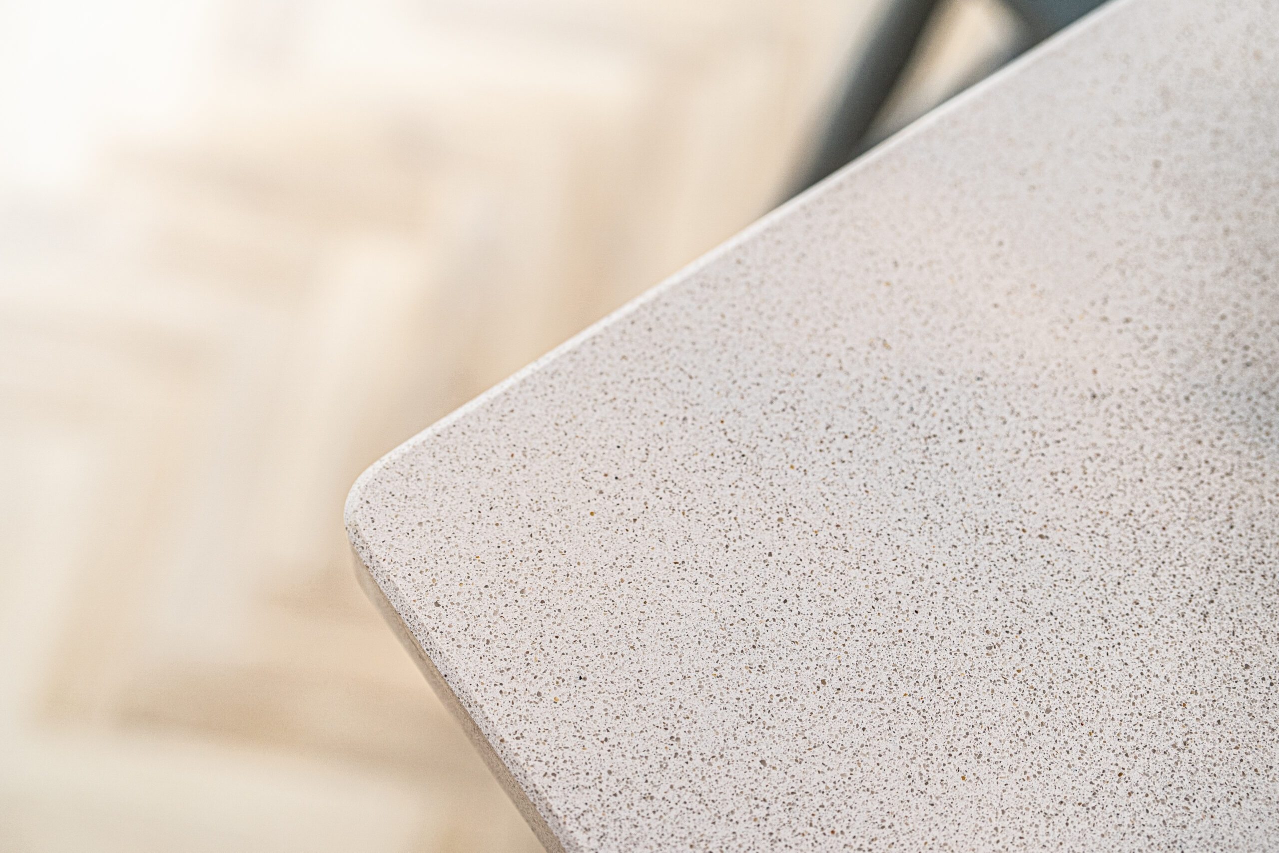 Close-up of Ice White Quartz worktop corner showing a rounded edge and fine speckled surface finish
