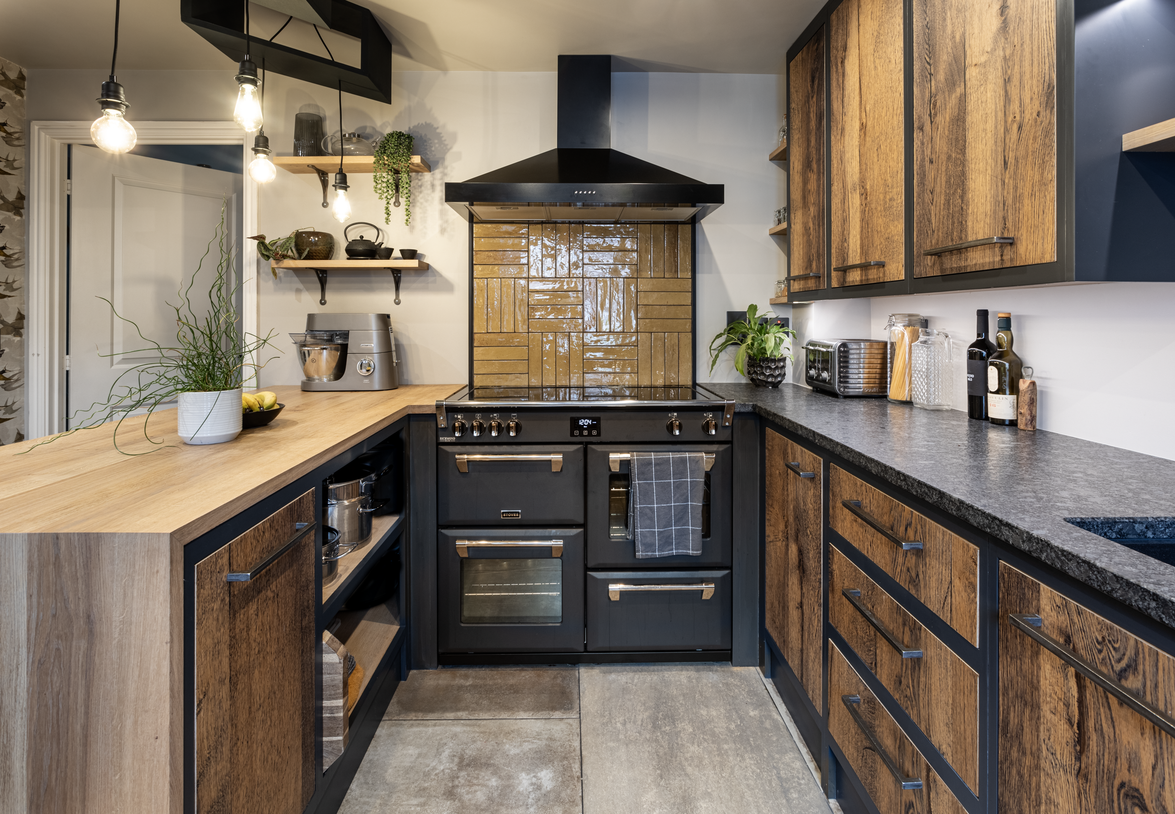 Wide kitchen view with Steel Grey leather Granite worktops on both sides, showing the textured Granite finish, rustic wood cabinetry and a black range cooker.