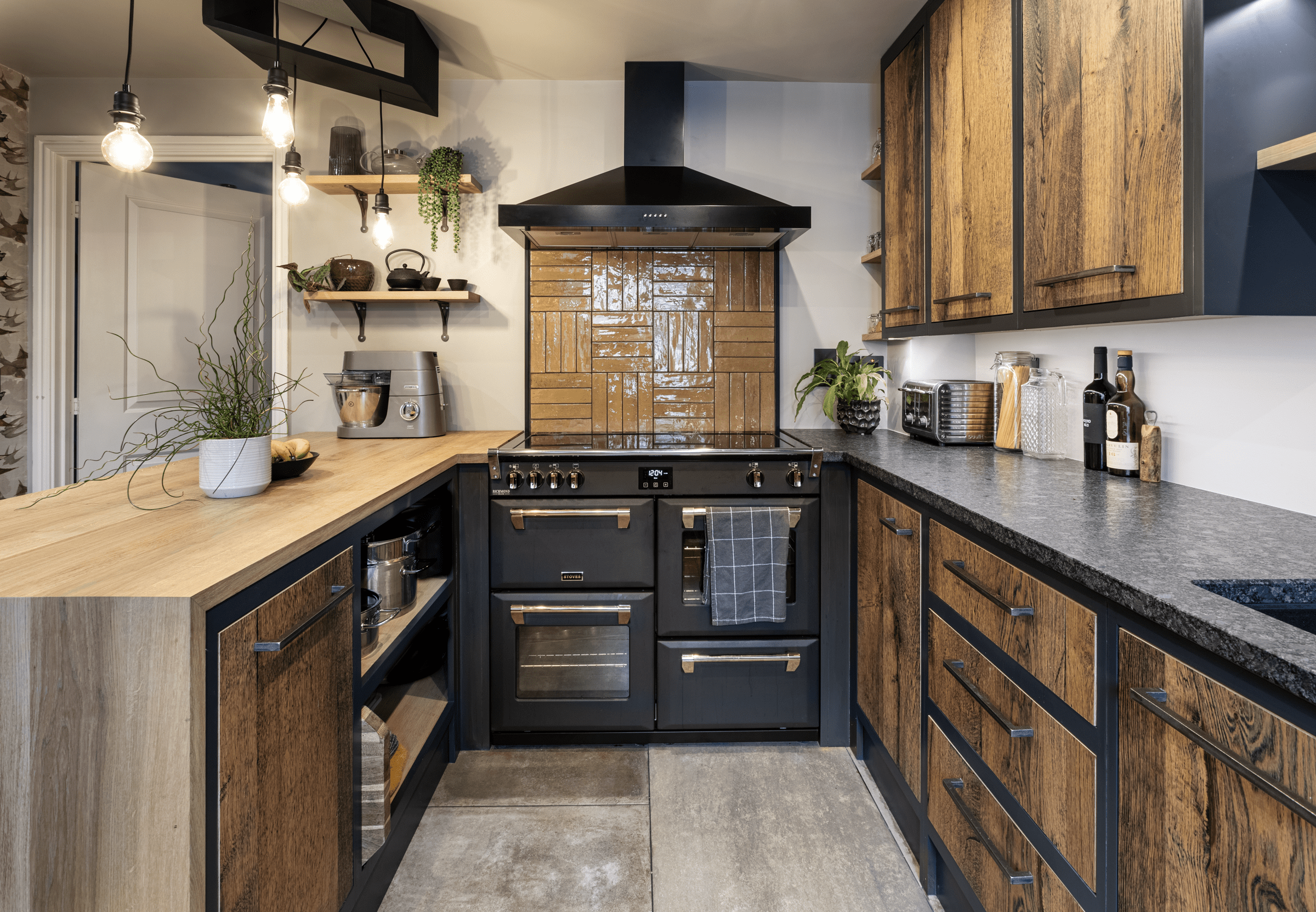 Wide kitchen view with Steel Grey leather Granite worktops on both sides, showing the textured Granite finish, rustic wood cabinetry and a black range cooker.