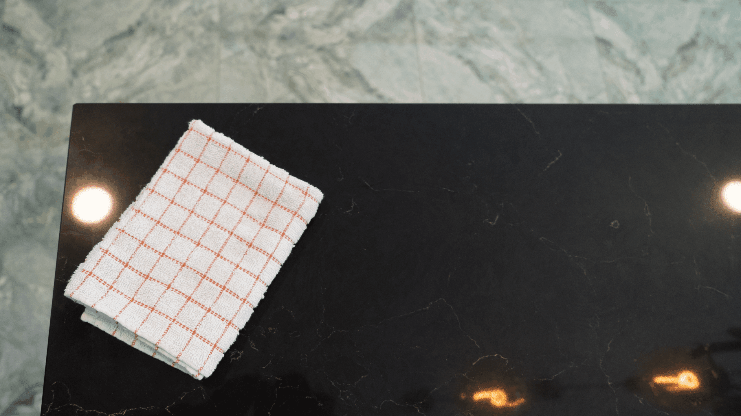 Emperor Black Quartz worktop close-up with polished black surface and delicate veining beside a folded cloth