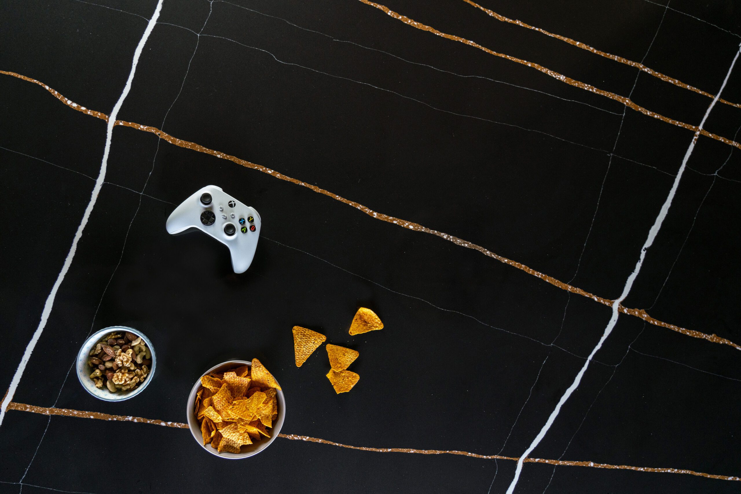 Sahara Noir Quartz surface shown from above with black background, gold veining bands and styling items for scale