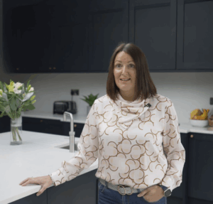 Customer standing in her kitchen with Carrara Quartz worktops installed by Mayfair Worktops