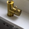 Close-up of a brass tap set into an Imperial White Quartz worktop with a smooth white finish