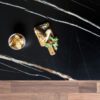 Noir St Laurent Porcelain worktop slab close up showing deep black surface with bold gold veining, styled with food and accessories