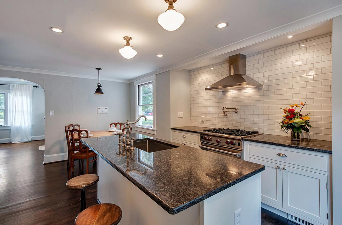Wide view of a modern kitchen with Steel Grey Granite worktops on the island and perimeter run, showing bar seating and pendant lighting above the island.
