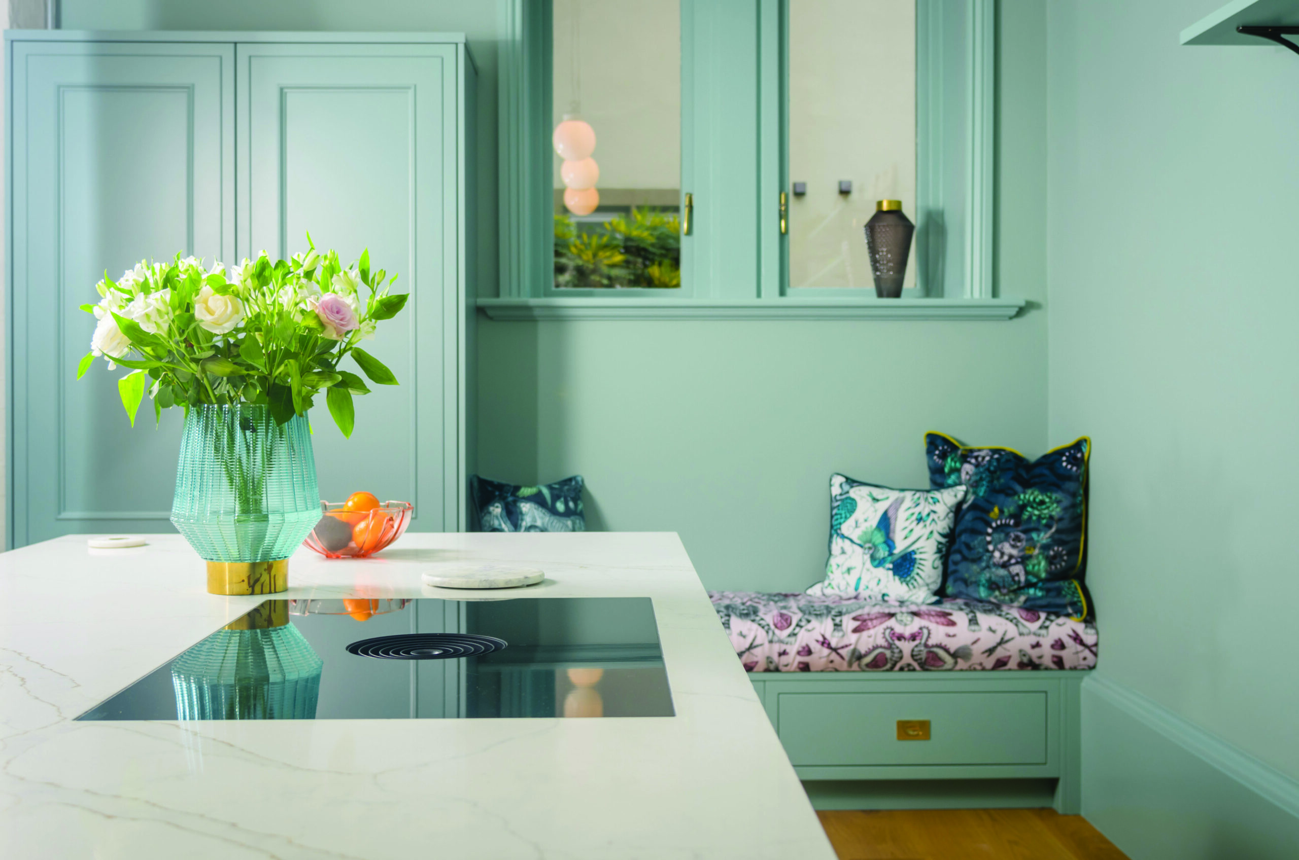 Gold Calacatta worktop with hob cut out beside a built in seating nook in a modern kitchen