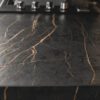 Laurent Porcelain worktop close-up showing dark stone-effect surface with strong gold veining under kitchen lighting.