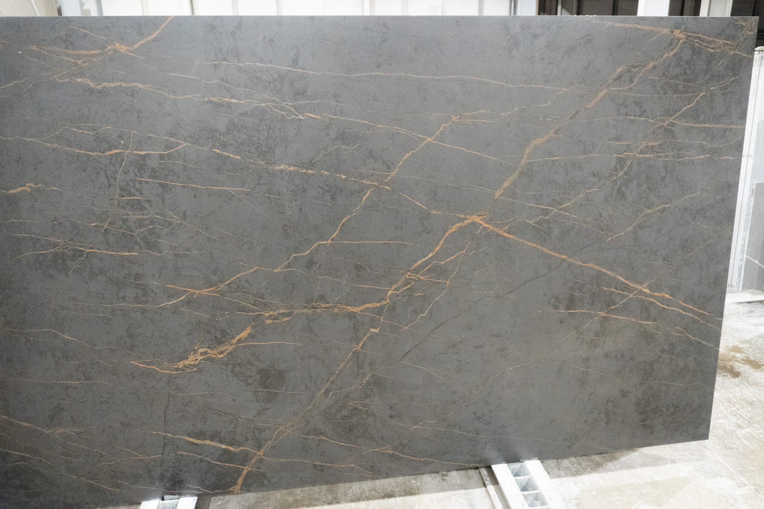Gold Laurent Porcelain slab in a warehouse setting with long gold veining lines across dark grey surface