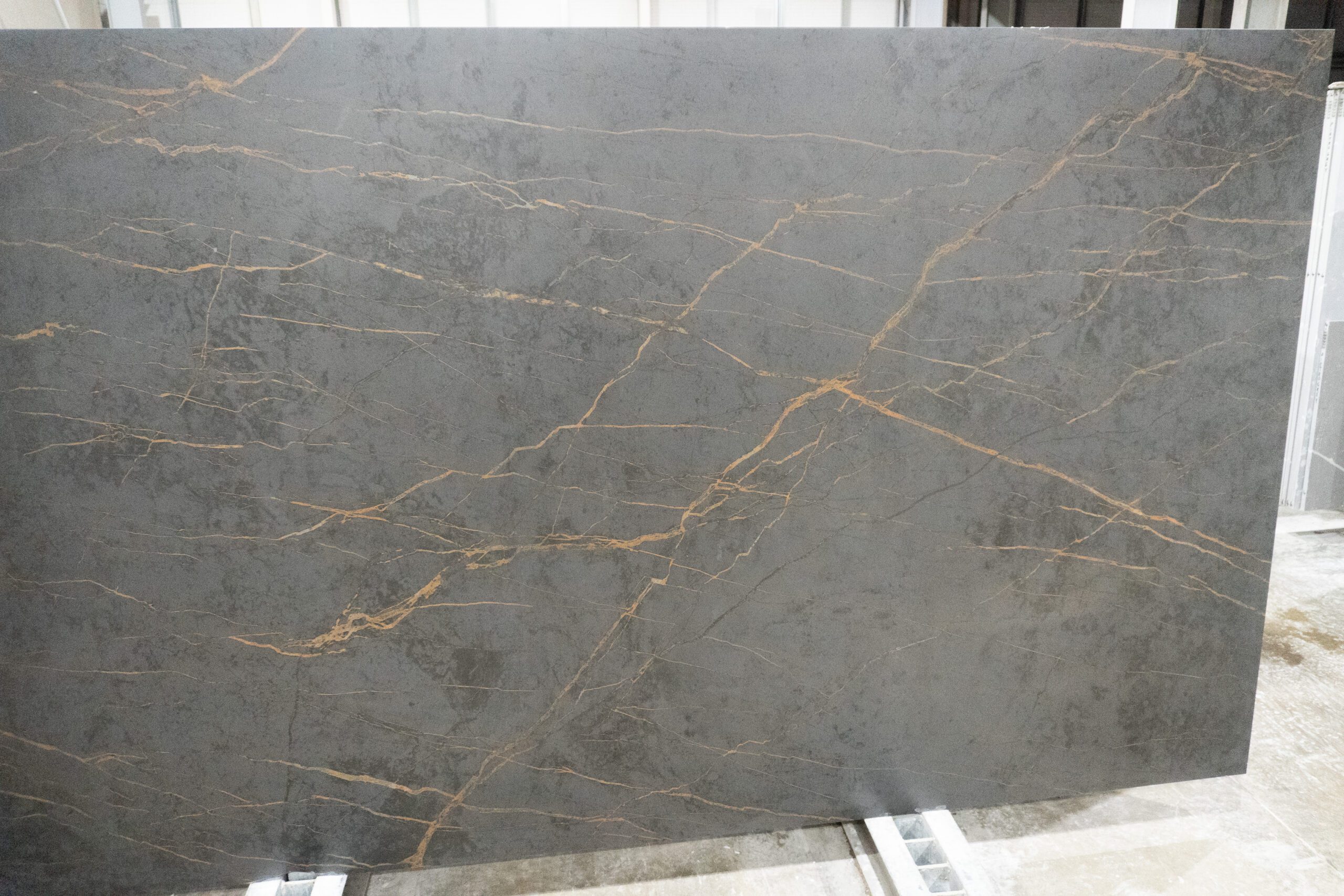 Gold Laurent Porcelain slab in a warehouse setting with long gold veining lines across dark grey surface