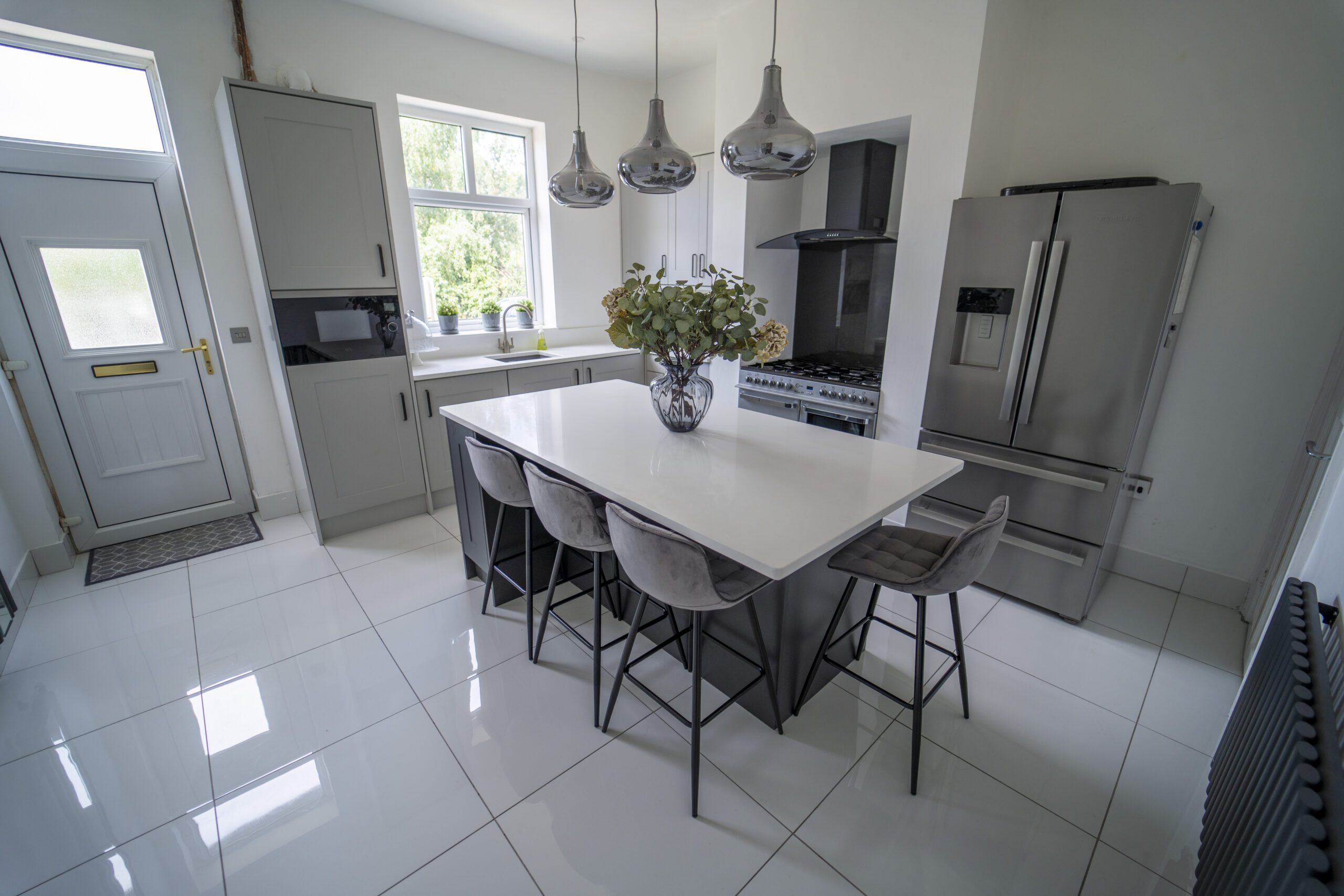 Modern kitchen with a Classic White Quartz island worktop and seating, showing a smooth white surface finish