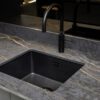 Laurent Porcelain worktop close-up around an undermount black sink with a black tap and gold veining through the surface.