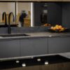 Laurent Porcelain worktop installed along a modern kitchen run with an undermount sink, black tap, and fruit bowl on the surface.